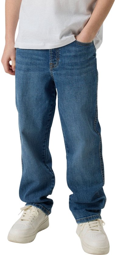 Jongen in een witte t-shirt en losse, blauwe jeans.