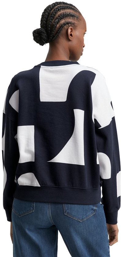 Achterkant model met donkerblauwe sweater met grote witte grafische print en spijkerbroek.