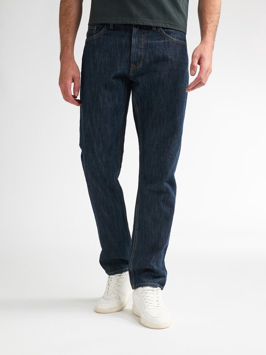 Man met donkerblauwe jeans en witte sneakers.