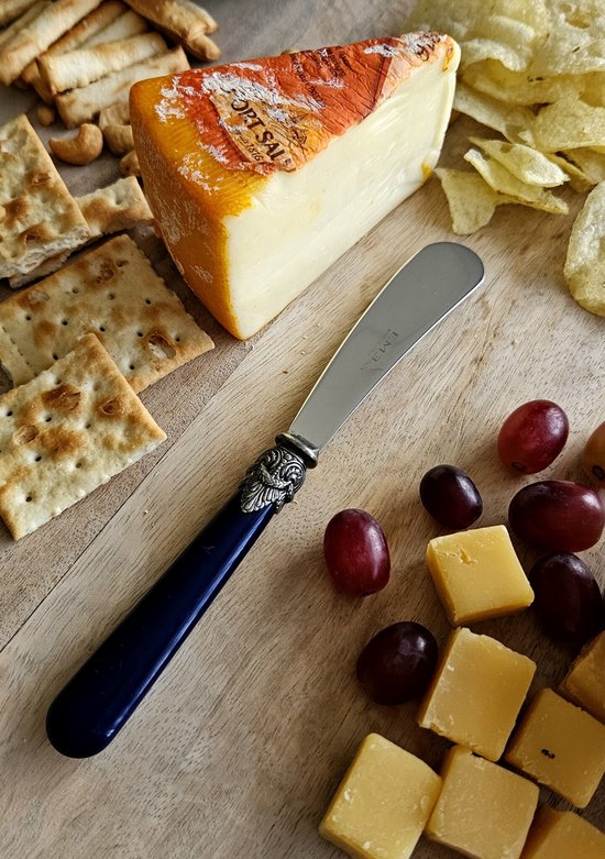 Een blauw botermesje met sierlijk zilverkleurig handvat ligt naast een stuk kaas, druiven, crackers en chips.