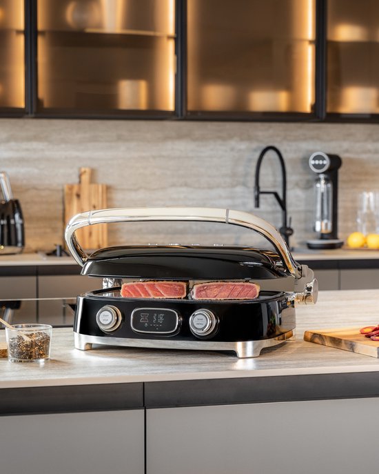 Zwarte contactgrill met chromen handgreep en tonijnsteaks, in een keuken.