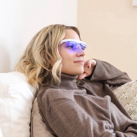 Vrouw met blond haar, draagt een AYOlite bril met blauw licht, zittend op een bank.