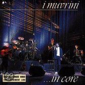 I Muvrini live concert met drums, gitaren, en zanger in wit jasje en blauwe das.
