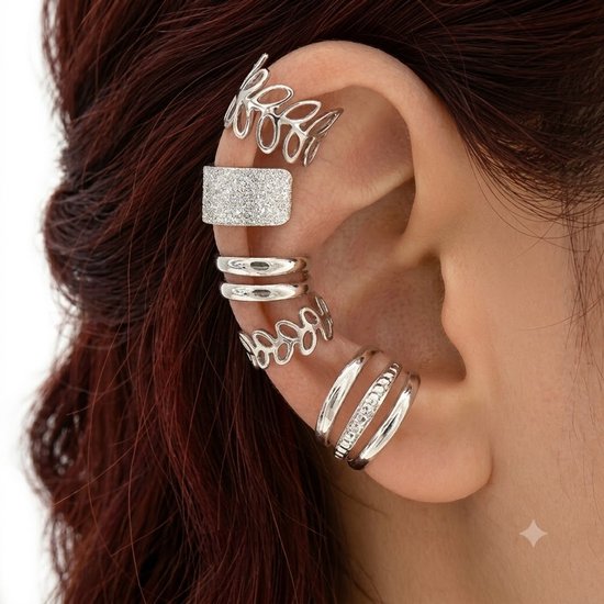 Een oor vol zilverkleurige ear cuffs: een opengewerkte bladring, een glitterrechthoek, twee dubbele ringen en een drievoudige ring met steentjes.