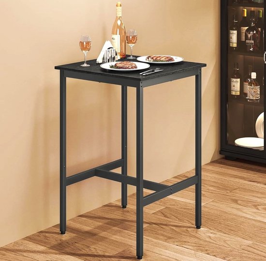 Hoge, vierkante tafel met zwart houten blad en metalen onderstel. Getoond met twee wijnglazen, borden met eten en een fles wijn.