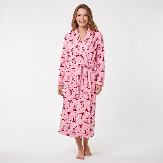 Vrolijke vrouw in een roze badjas met een rode strijesprint, staand.