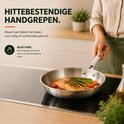 Een vrouw kookt zalm, asperges en tomaten in een Organess RVS koekenpan met hittebestendige greep.