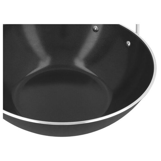 Detail van de zwarte binnenkant van een wokpan met zilveren rand.