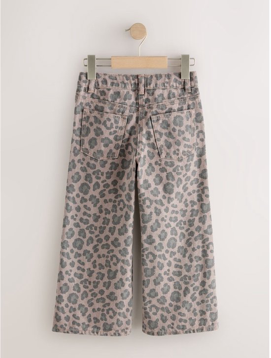 Achterzijde van een spijkerbroek met wijde pijpen, taupekleurig denim met grijs luipaardpatroon, hangend aan een hanger.