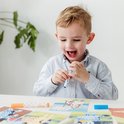 Jongetje met gestreepte blouse kijkt blij naar zijn stempelwerk op een Bluey kaart.