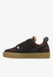 Zijprofiel van donkerbruine suède sneakers met crèmekleurige zool en teddy voering. "SHABBBIES" logo op de hielband.