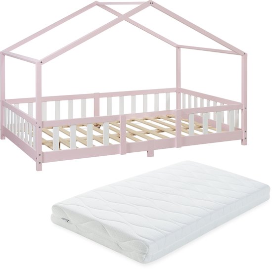 Roze kinderhuisbed met witte spijlen en een losse witte matras.