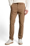 Model in een bruine chino en grijze sneakers.