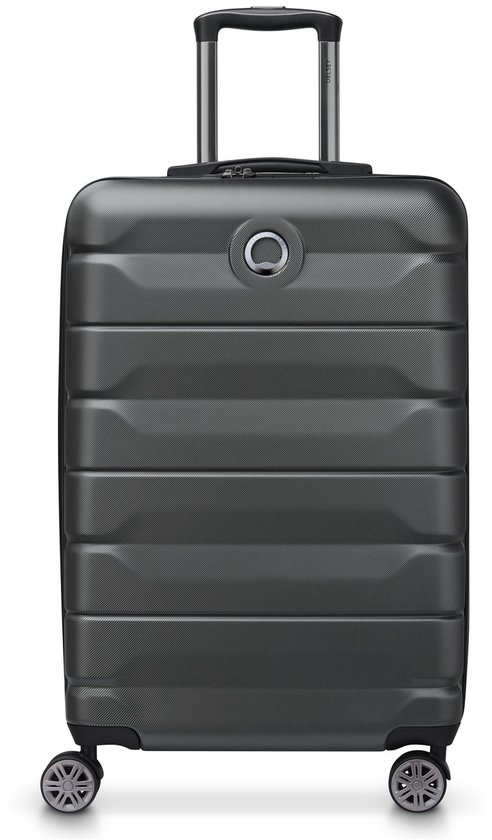 Donkergrijze Delsey koffer met horizontale ribbels, uitschuifbaar handvat en vier wielen.