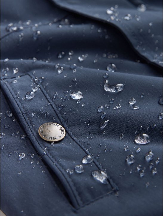 Detailopname van donkerblauwe, waterdichte stof met waterdruppels en knoop van een jas.