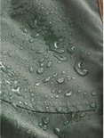 Detailopname van de waterafstotende groene stof van de parka met regendruppels op het oppervlak.