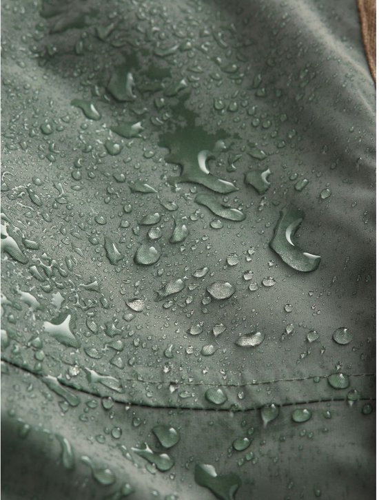 Detailopname van de waterafstotende groene stof van de parka met regendruppels op het oppervlak.