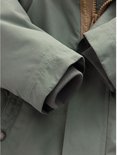 Detailopname van de mouwen van de groene parka, afgewerkt met grijze geribbelde boorden.