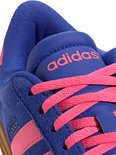 Close-up van de veters, tong en zijkant van een blauwe Adidas sneaker met roze strepen en Adidas logo.