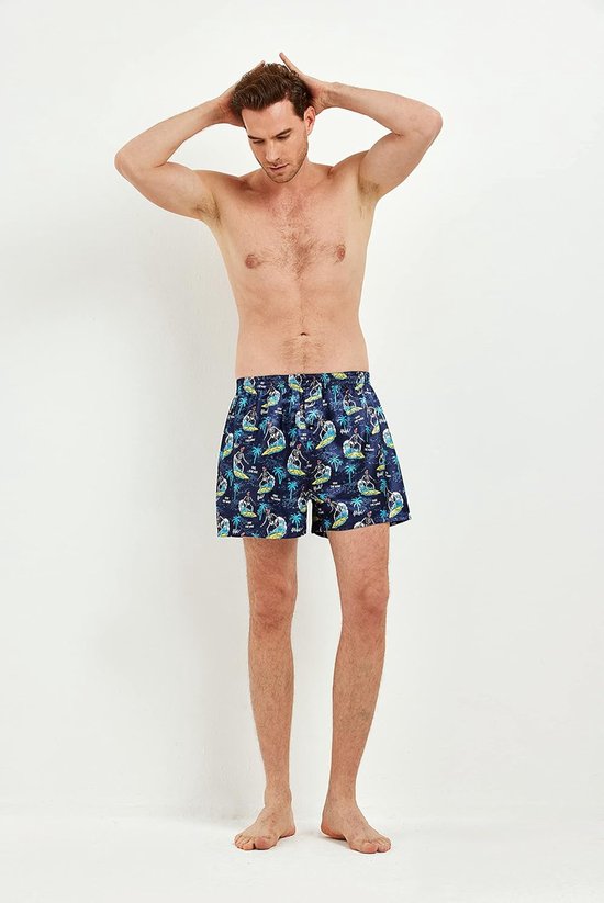 Model draagt een donkerblauwe satijnen boxershort met een print van surfende skeletten en palmbomen.