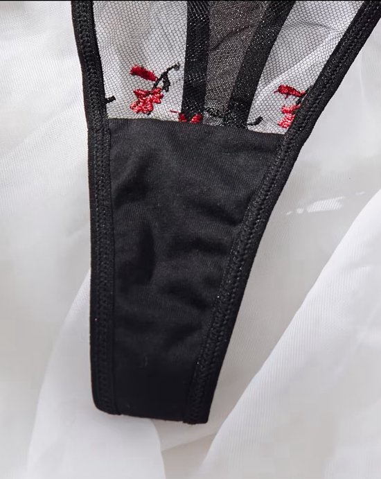 Detail van een zwarte kanten string met rode bloemen en een effen zwart kruisje.