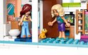 Twee LEGO Friends poppetjes, één in een geel topje en blauwe broek, de ander in een turquoise topje en paarse broek, staan met een klein geel beestje.