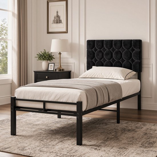 Tête de lit noire rembourrée avec motif circulaire sur un cadre de lit en métal noir, préparée avec un matelas et un plaid.