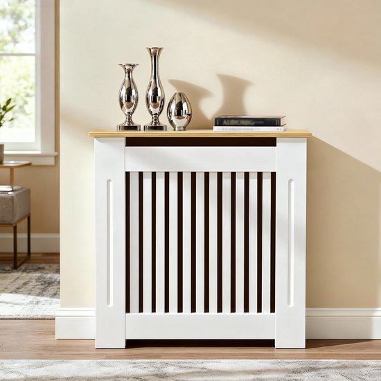 Wit radiatorombouw met houten bovenblad, versierd met zilveren vazen en boeken, in een woonkamer.