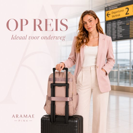 Vrouw met roze blazer en witte broek bij een luchthaven met een roze rugzak op een zwarte koffer.