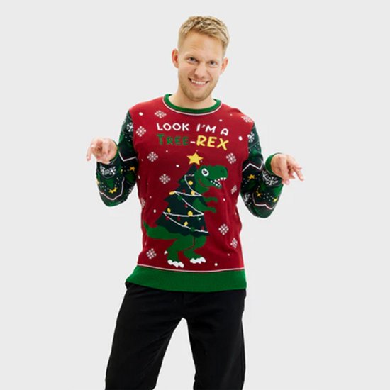 Een man wijst naar de dinosaurus op zijn rode kersttrui, die verkleed is als kerstboom met lichtjes en de tekst "LOOK I'M A TREE-REX".