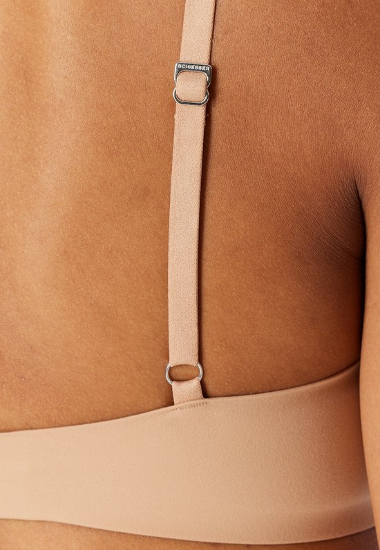 Close-up van een verstelbaar bandje met Schiesser-logo op de rug van een model, gedragen met een beige, naadloze bh.