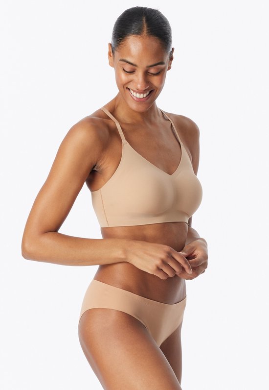 Model draagt een beige, naadloze bustier en bijpassende slip. V-hals en dunne bandjes.