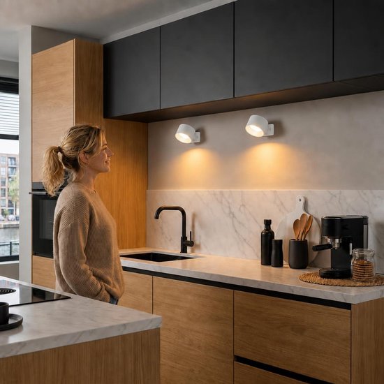 Moderne, witte, oplaadbare wandlamp met dimbare verlichting boven een marmeren aanrechtblad in een keuken.