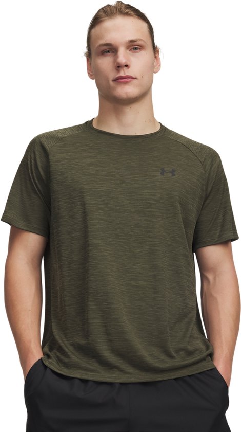 Model draagt marine OD groen sportshirt met korte mouwen, textuur en zwart Under Armour logo.