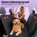 Une femme attache des clips orange à une housse de voiture noire matelassée, avec un golden retriever sur la banquette arrière.