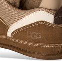 Detail van bruine UGG-sneaker met beige en witte biezen en UGG-logo.