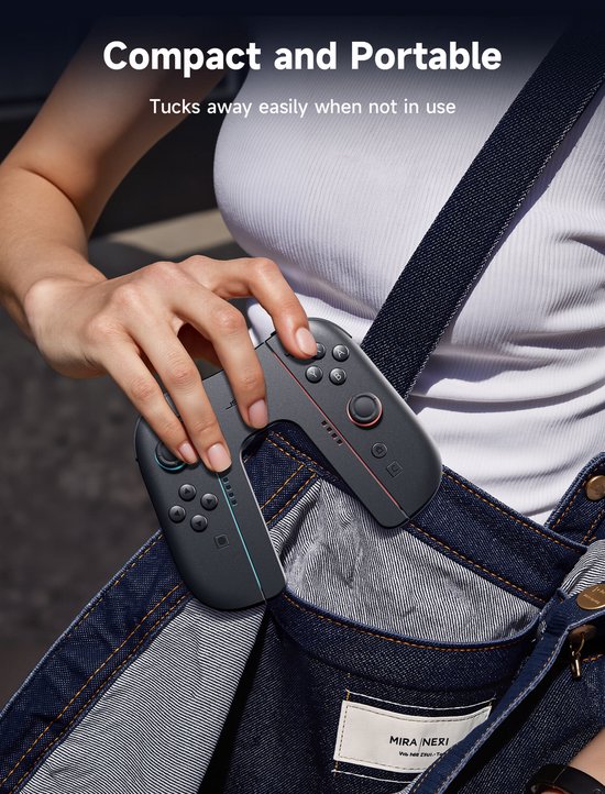 Een hand houdt een zwarte JSAUX Joy-Con controller vast, die in een denim tas wordt gestopt. Compact en draagbaar.