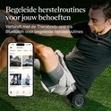 Man gebruikt een zwarte schuimroller op zijn been, gekoppeld aan de Therabody app op zijn telefoon.