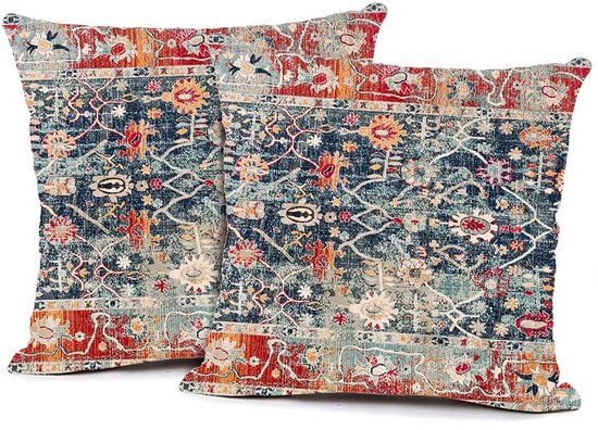Deux coussins avec un motif de tapis bohème détaillé et vieilli dans des tons de bleu, rouge et orange.
