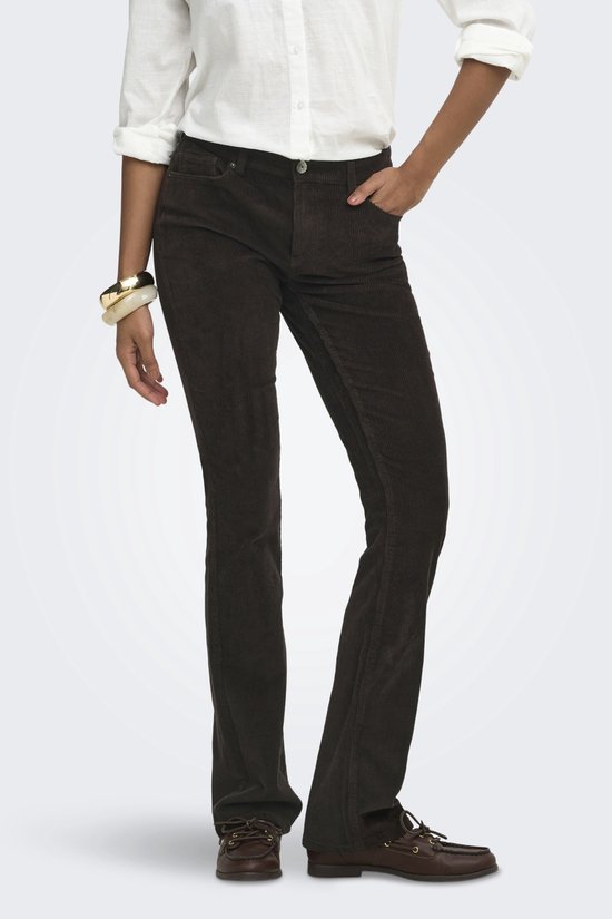 Model draagt een bruine corduroy flared broek met witte blouse en bruine schoenen.