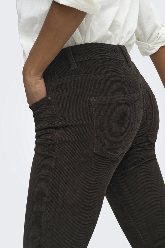 Bruine ribbroek met achterzakken, gedragen door een model met een witte blouse.