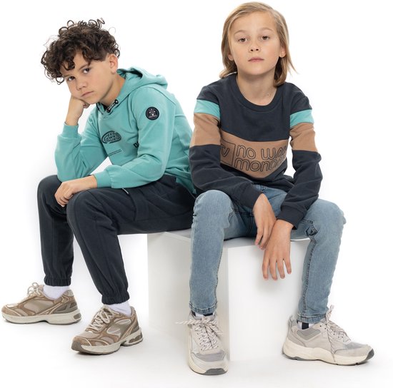 Twee jongens die op witte kubussen zitten. Links een jongen in een mintgroene hoodie, rechts een jongen in een donkergrijs shirt met kleurblokken.