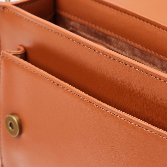 Detail van de bruine tas met naad en knoop.