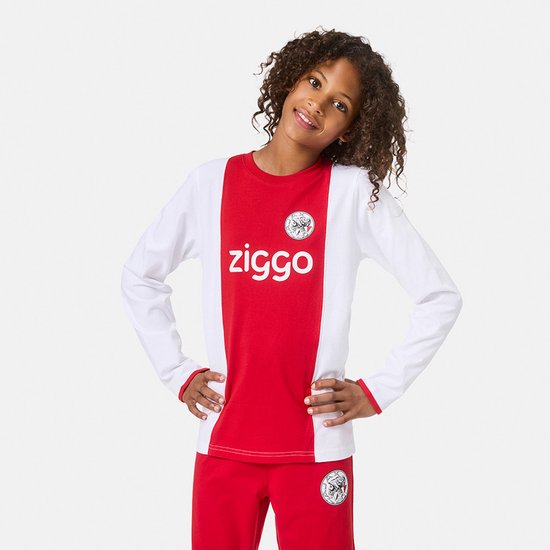 Jongen draagt een rood-wit Ajax pyjamashirt met Ziggo logo. Lange mouwen, ronde hals en Ajax-logo op de borst.