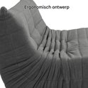 Detailopname van de plooien en gewatteerde textuur van een grijze vloersofa.