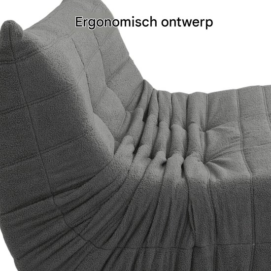 Detailopname van de plooien en gewatteerde textuur van een grijze vloersofa.