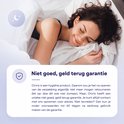 Een jonge vrouw met gesloten ogen en een glimlach slaapt op haar zij in een wit bed.