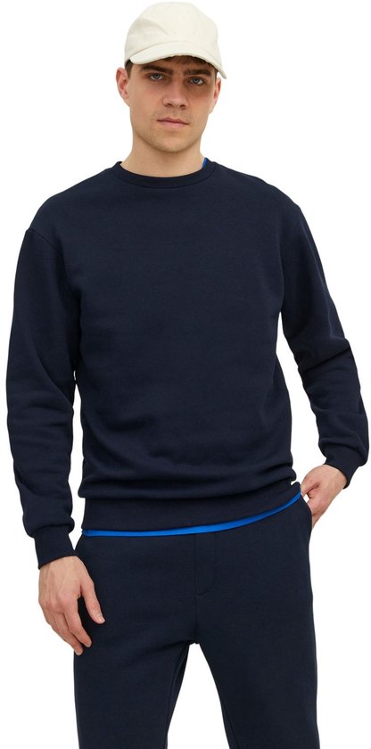 Donkerblauwe longsleeve sweater met ronde hals, gedragen door een man met een beige pet.