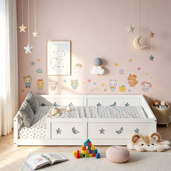 Wit Montessori kinderbed met sterren- en maanmotief, kussens en speelgoed op roze muur.