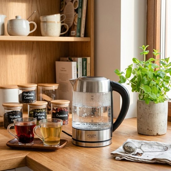 Glazen waterkoker met RVS details, met twee kopjes gevuld met thee.